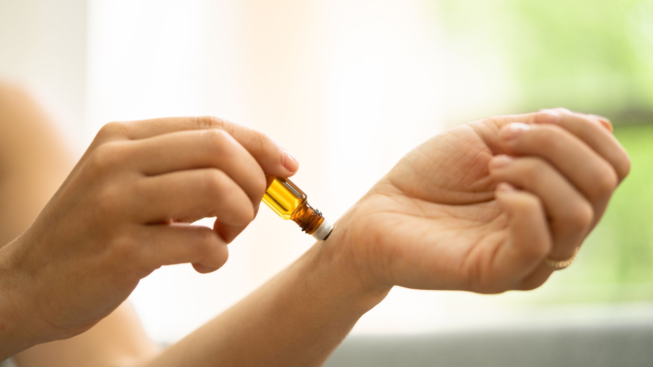 Hands applying essential oil to the wrist during aromatherapy